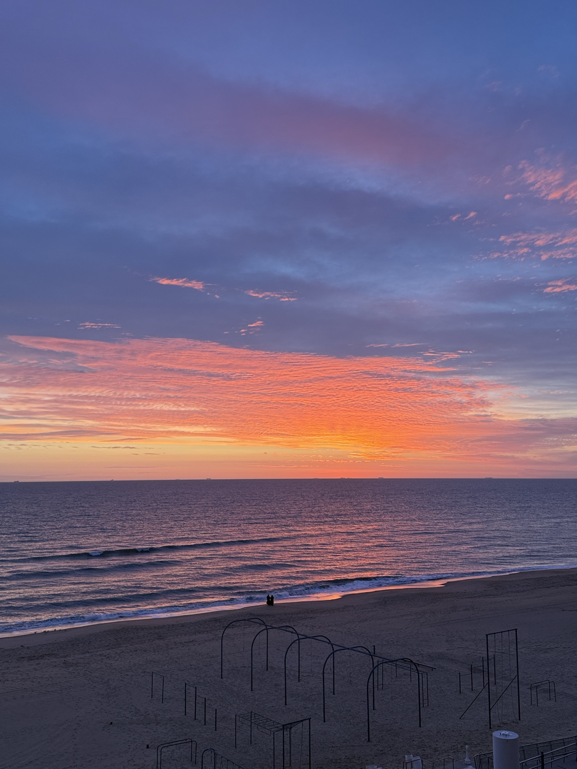 Pink and blue clouds above a quiet beach and gentle waves