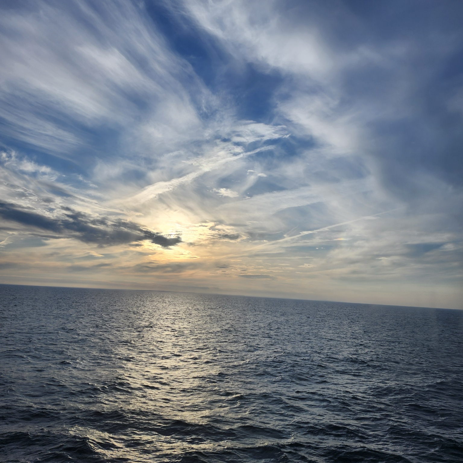 Soft sunlight shining through sweeping clouds above the blue ocean